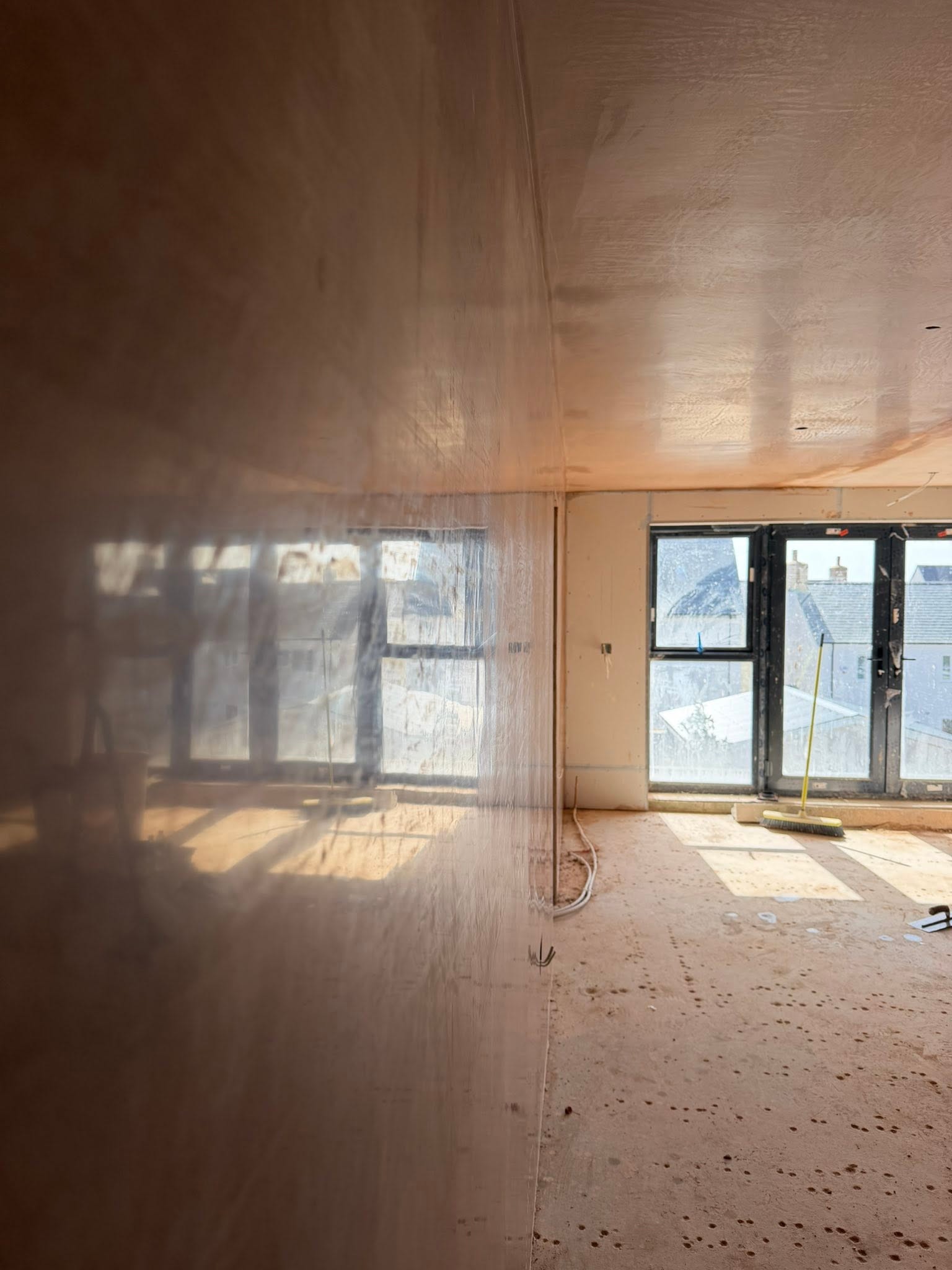 Warm brown plastered walls and ceiling reflecting the large glazed doors