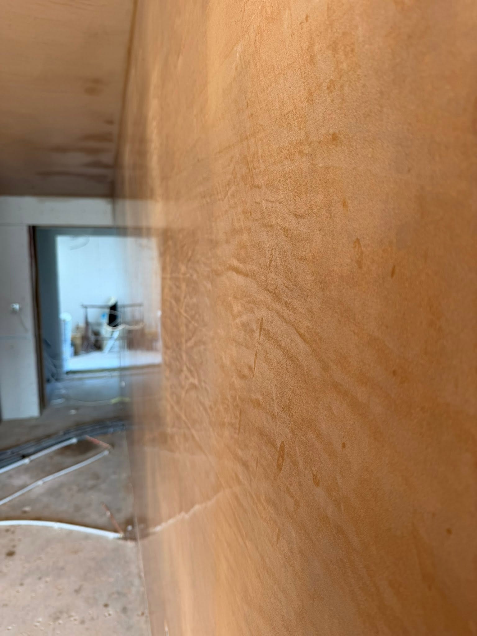 Close view of warm orange plaster with a doorway reflected in its surface