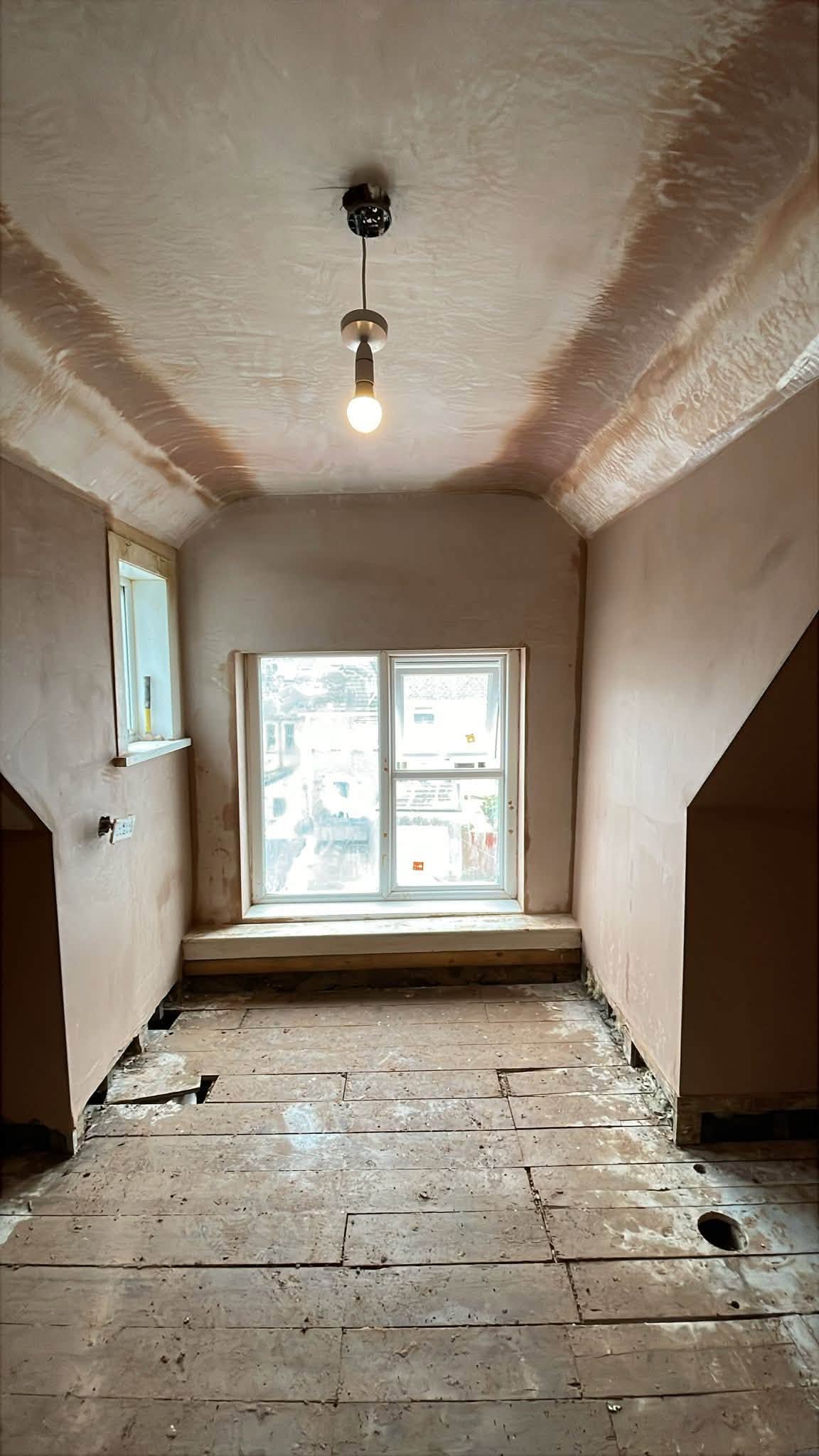 Room with a freshly plastered sloping ceiling and white-framed window