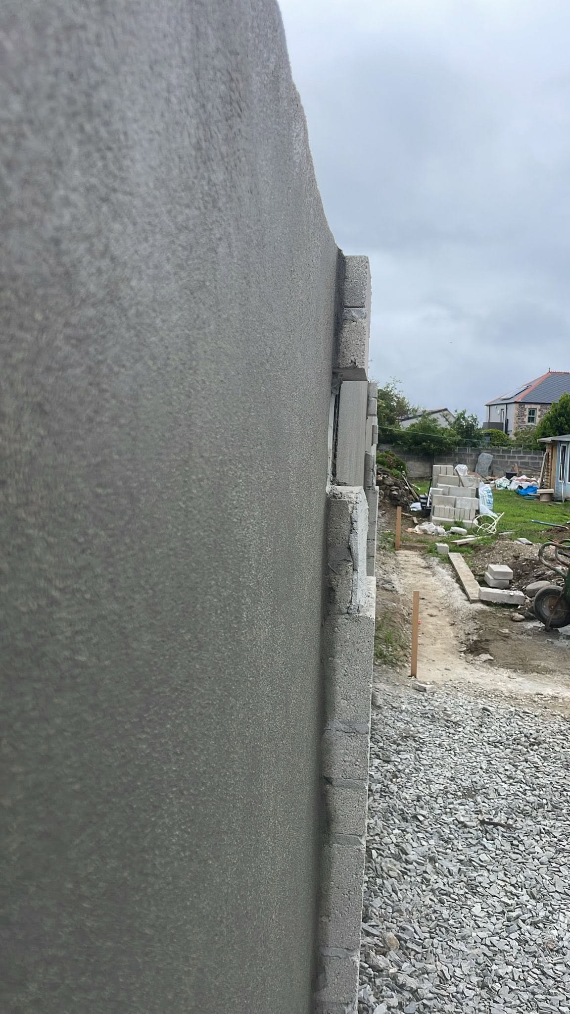 Grey top coat seen along the boundary wall beside a white building